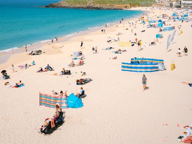People relaxing on a sandy beach with a turquoise sea